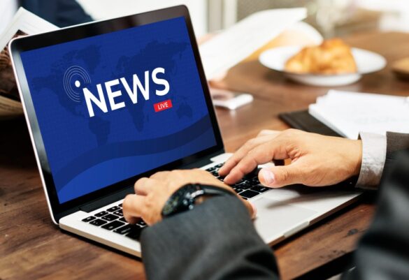 Homme lisant les News en direct sur un ordinateur portable, travaillant sur un bureau en bois.